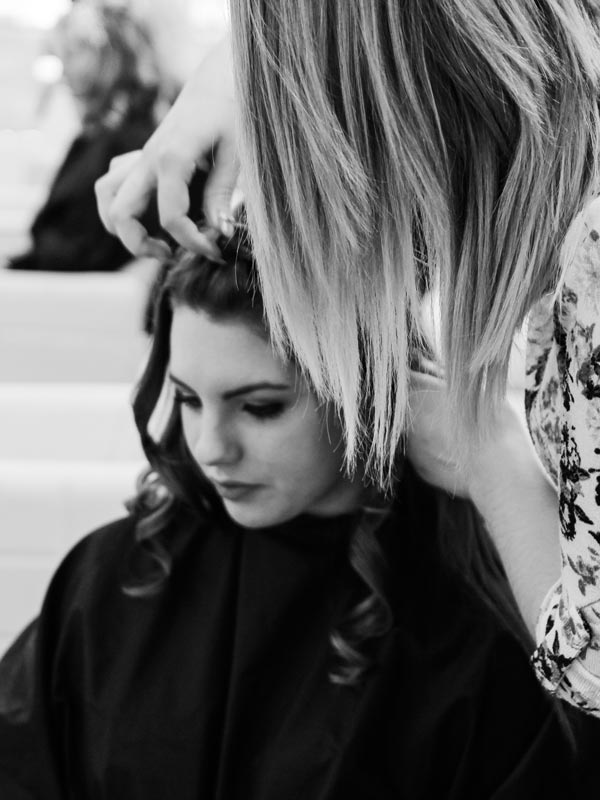 Eine junge Friseurin macht Haar-Styling einer jungen Frau